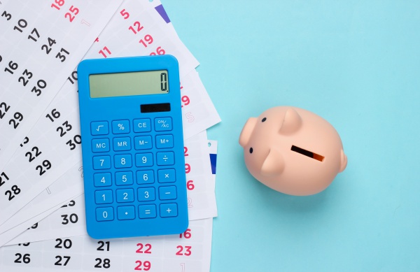Piggy bank with a monthly calendar, calculator on a blue background. Payment of rental housing or loans. Top view